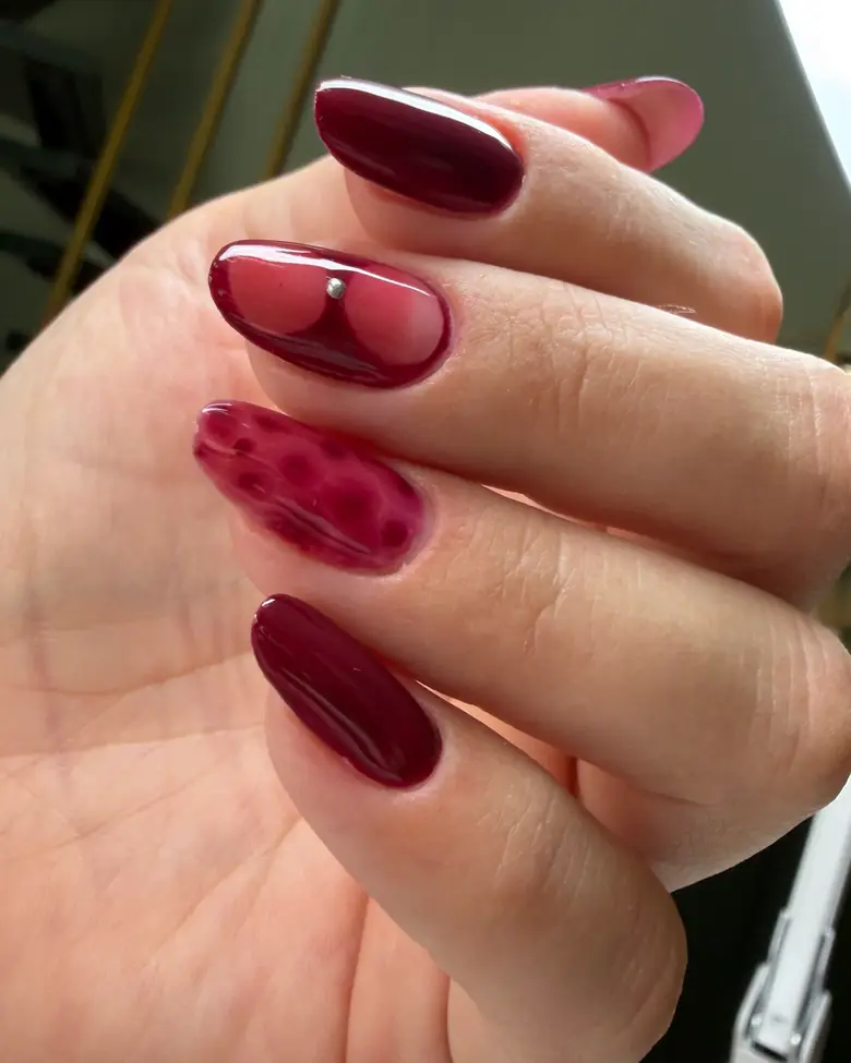 Uñas burdeos con diseño de animal print y aplicación plateada
